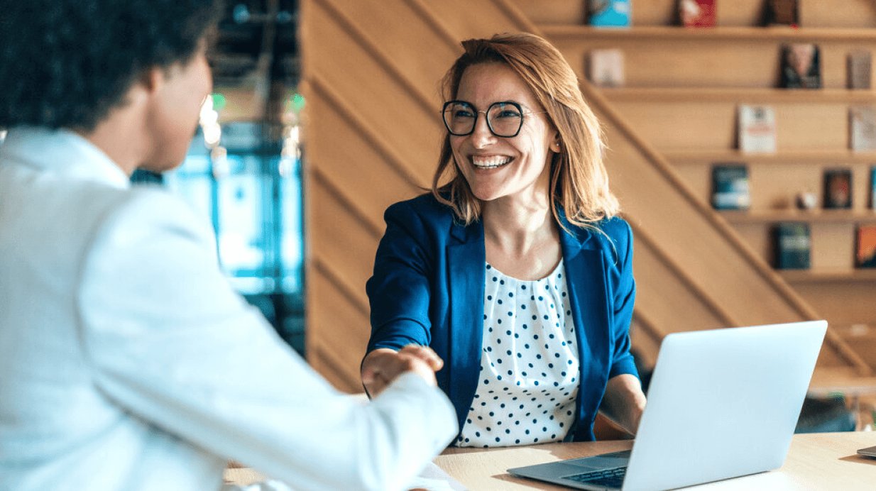 A smiling insurance agent meeting with a client for a coverage review.